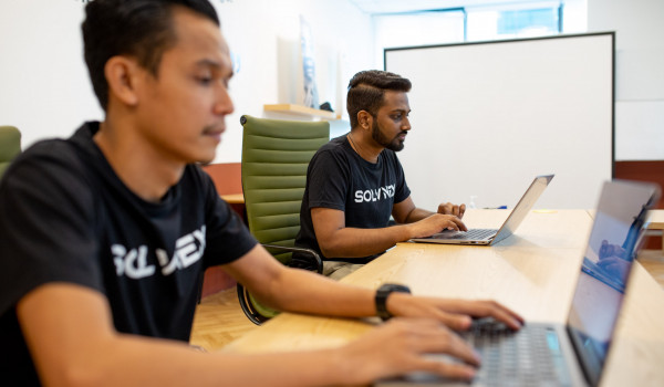 Qadir Hairi (CEO of SOLVNEX) and a colleague working on their laptops.