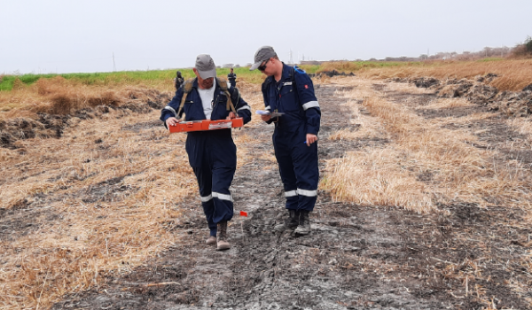 Two workers checking for pipeline anomalies using the Magnetic Tomography Method